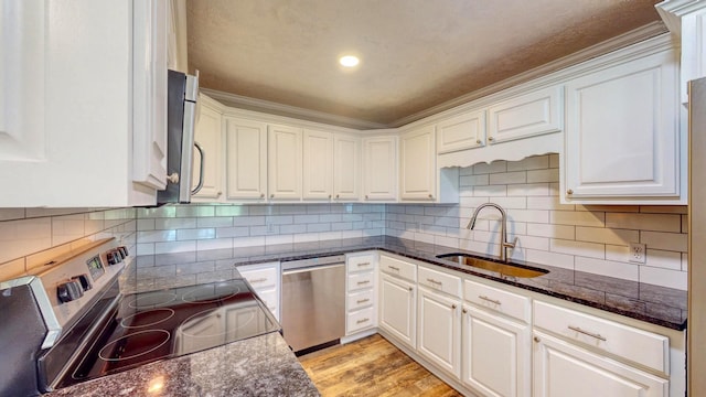 kitchen with white cabinetry, appliances with stainless steel finishes, sink, and dark stone counters