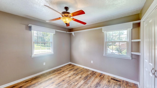 unfurnished room featuring hardwood / wood-style flooring, ceiling fan, and a textured ceiling