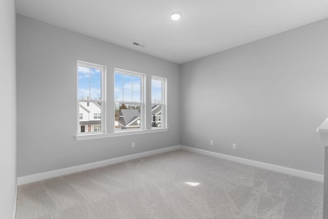 carpeted spare room featuring visible vents and baseboards