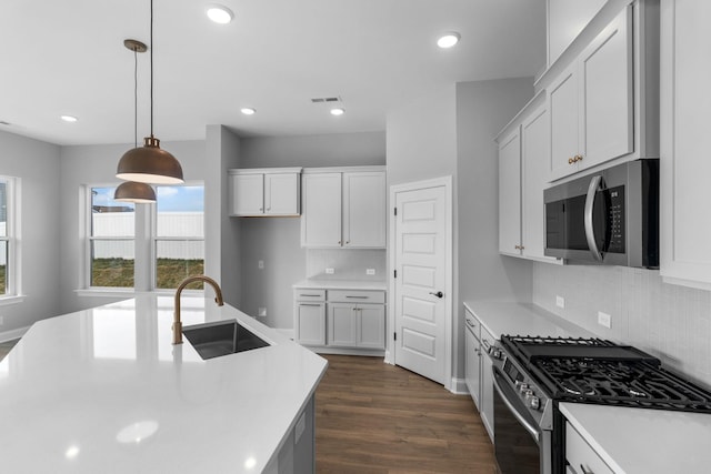 kitchen featuring dark wood-style flooring, decorative light fixtures, stainless steel appliances, light countertops, and a sink