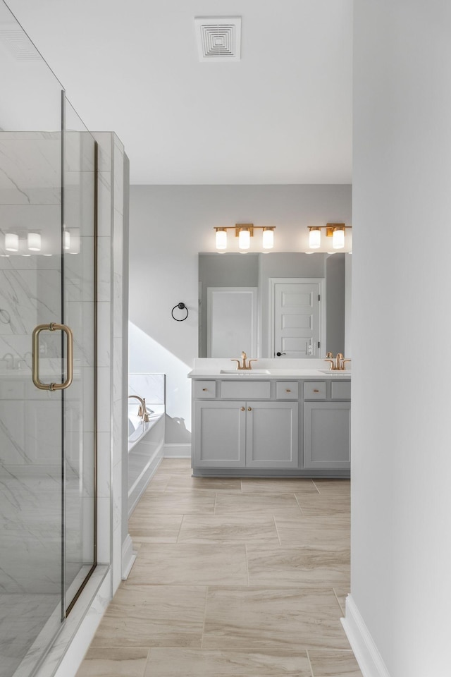 full bathroom featuring a garden tub, a marble finish shower, double vanity, visible vents, and a sink