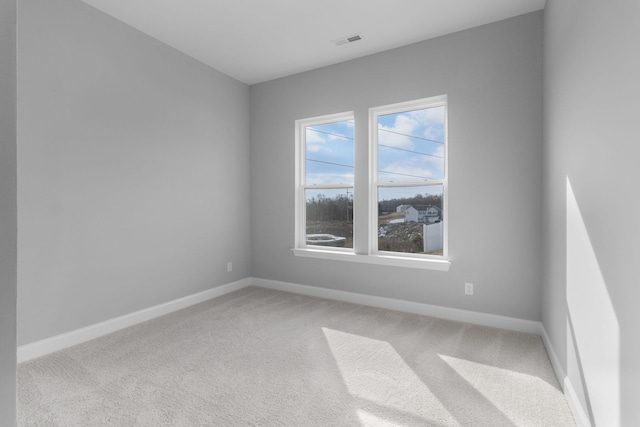 carpeted spare room with visible vents and baseboards