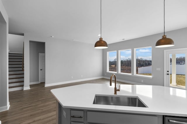 kitchen with dark wood-style floors, open floor plan, hanging light fixtures, light countertops, and a sink