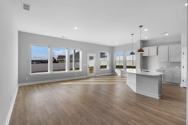 kitchen with decorative light fixtures, visible vents, backsplash, dark wood-type flooring, and a sink