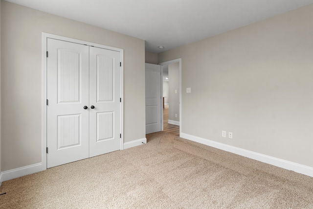 unfurnished bedroom with a closet and light colored carpet