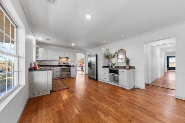 kitchen featuring open shelves, appliances with stainless steel finishes, dark countertops, and under cabinet range hood