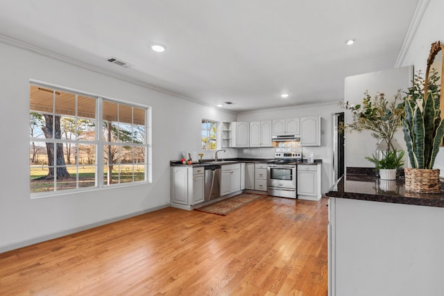 kitchen featuring dark countertops, under cabinet range hood, appliances with stainless steel finishes, and crown molding