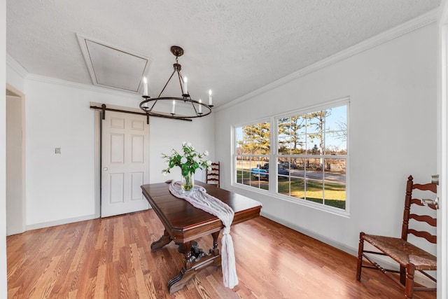 dining area with light wood finished floors, crown molding, a textured ceiling, and a barn door