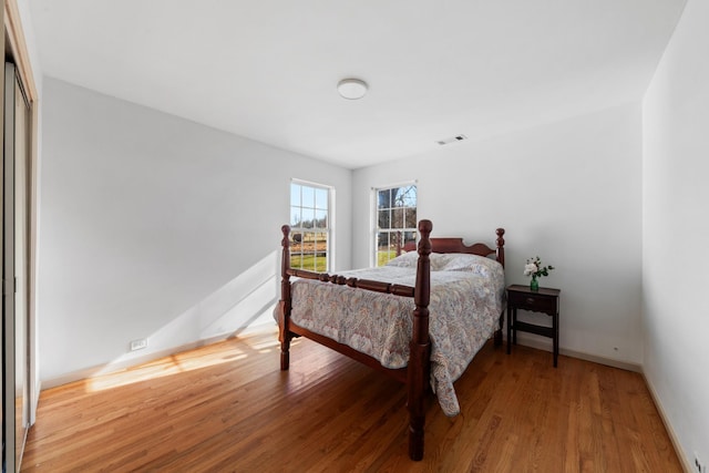 bedroom featuring baseboards, visible vents, and wood finished floors