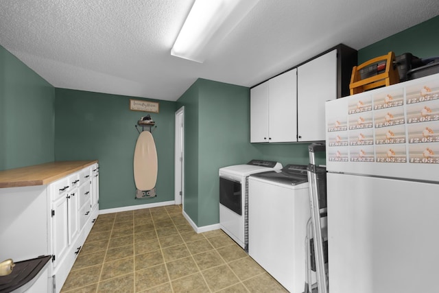 laundry room featuring cabinets, tile patterned floors, washing machine and clothes dryer, and a textured ceiling