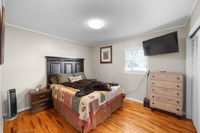 bedroom featuring a closet, ornamental molding, light hardwood / wood-style flooring, and a textured ceiling