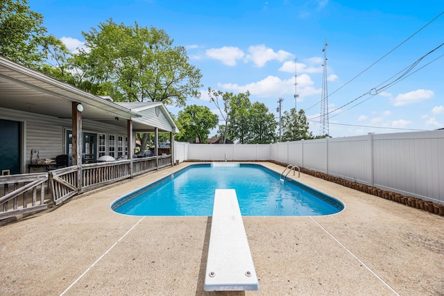 view of swimming pool with a patio area and a diving board