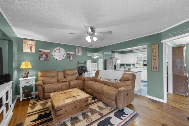 living room with ceiling fan, crown molding, a textured ceiling, and light hardwood / wood-style floors