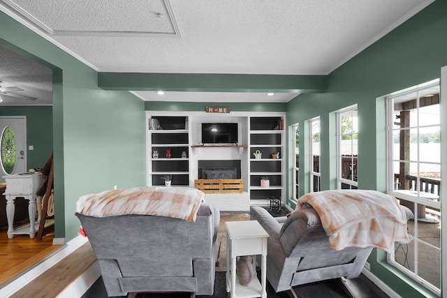 living room with hardwood / wood-style flooring, ornamental molding, ceiling fan, a brick fireplace, and a textured ceiling