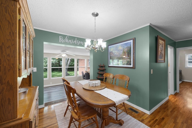 dining space with an inviting chandelier, ornamental molding, wood-type flooring, and a textured ceiling