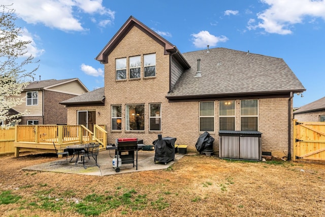 rear view of property with a deck, a patio area, and a lawn