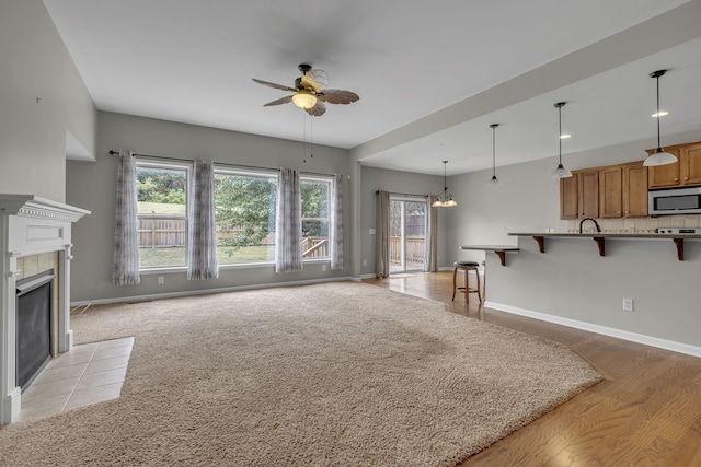 living room with a tiled fireplace and ceiling fan