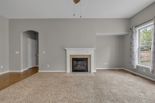 unfurnished living room featuring light carpet, a fireplace, and ceiling fan