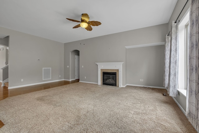 unfurnished living room featuring light colored carpet, a tile fireplace, and ceiling fan