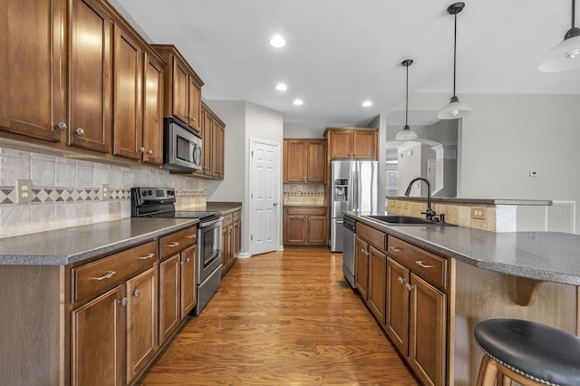 kitchen with a breakfast bar, sink, decorative light fixtures, appliances with stainless steel finishes, and an island with sink