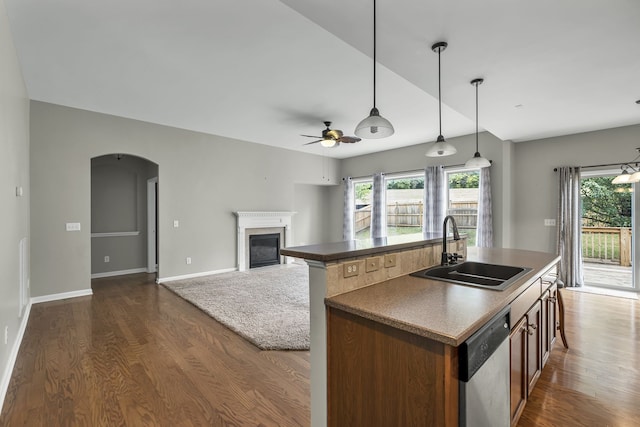 kitchen featuring stainless steel dishwasher, sink, an island with sink, and hanging light fixtures