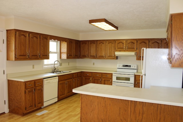 kitchen with white appliances, sink, kitchen peninsula, light hardwood / wood-style floors, and a textured ceiling