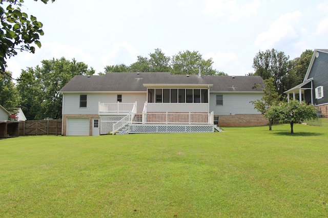 rear view of property with a garage, a yard, a sunroom, and a wooden deck