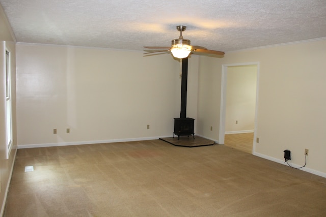 unfurnished living room with a wood stove, a textured ceiling, light colored carpet, and ceiling fan