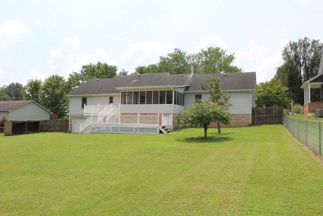 rear view of property featuring a yard, a sunroom, and a deck