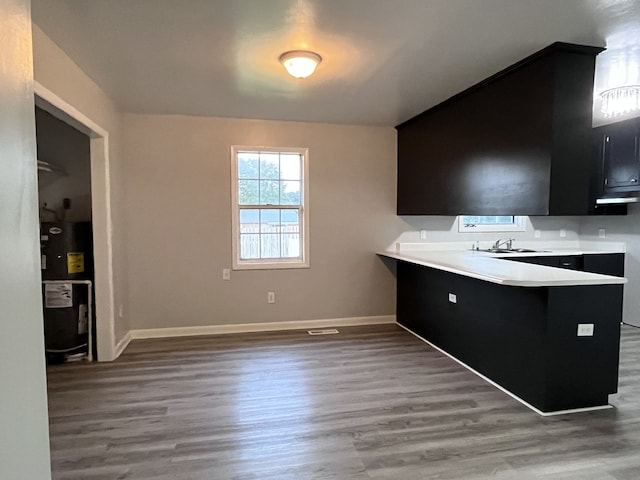 kitchen with wood-type flooring, water heater, sink, and kitchen peninsula