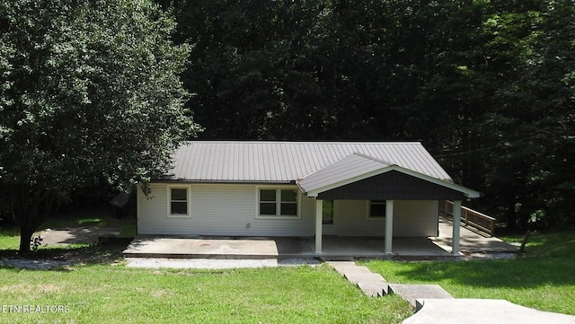 rear view of house featuring a yard, metal roof, and a patio area