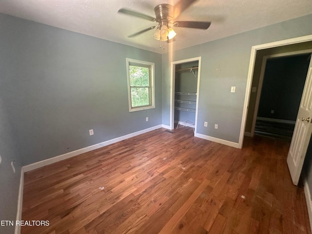 unfurnished bedroom featuring dark wood finished floors, a closet, baseboards, and a ceiling fan