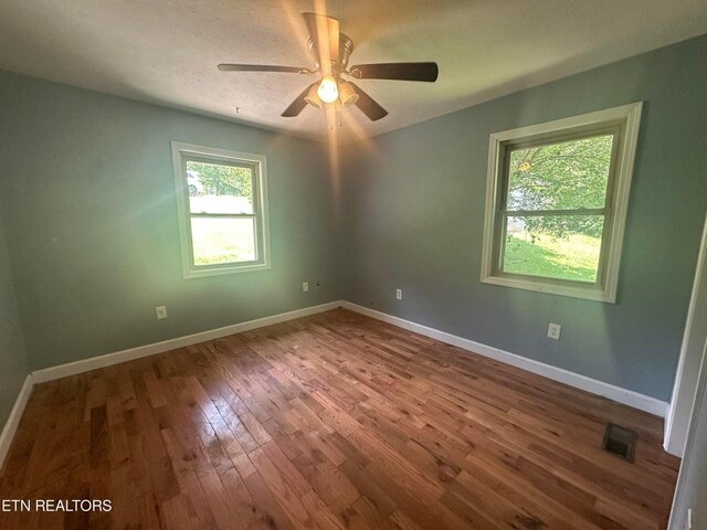 spare room with visible vents, baseboards, and wood finished floors