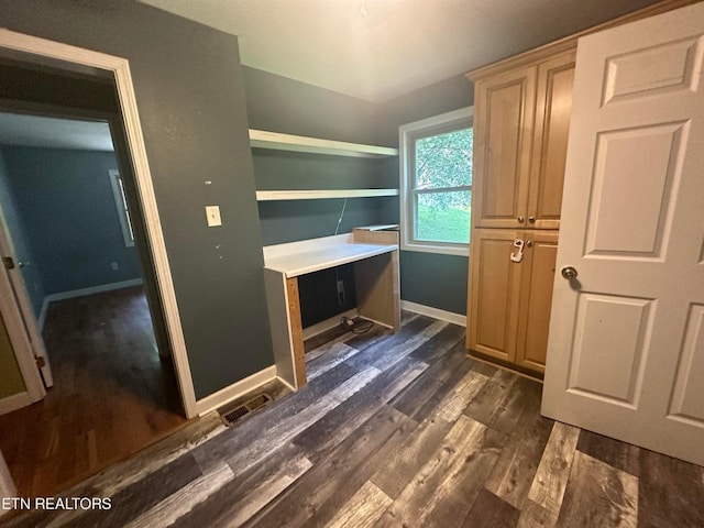 unfurnished office featuring visible vents, baseboards, and dark wood-type flooring