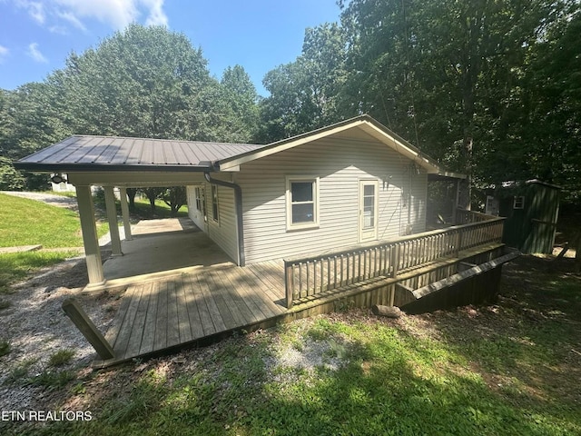 exterior space with a wooden deck, metal roof, and an outbuilding