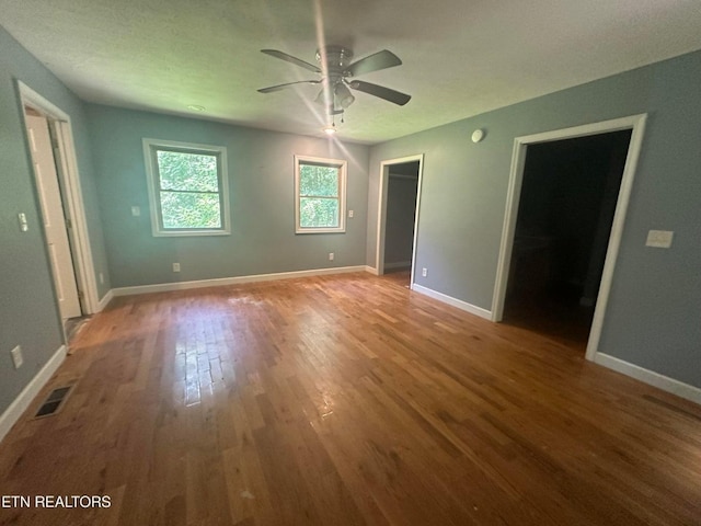 unfurnished bedroom featuring visible vents, baseboards, ceiling fan, and wood finished floors