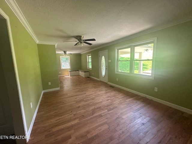 unfurnished room with a textured ceiling, ornamental molding, wood finished floors, and baseboards