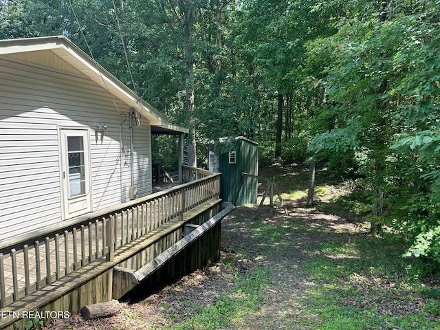 view of yard featuring an outdoor structure, a deck, and a storage shed