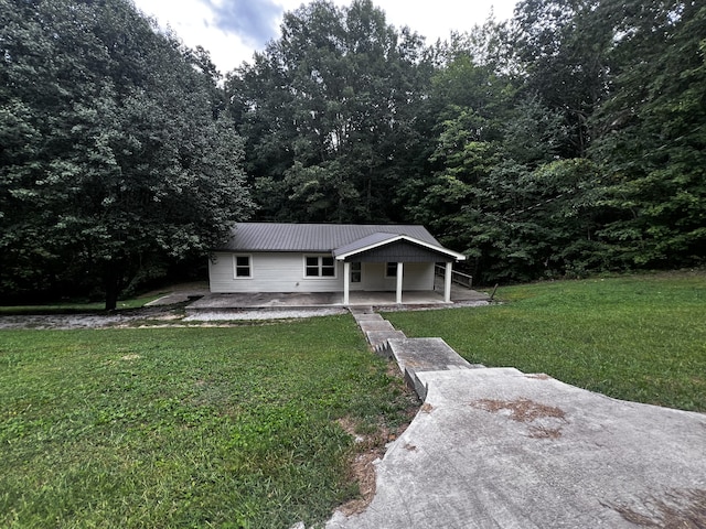 view of front of property with a patio area, metal roof, and a front yard