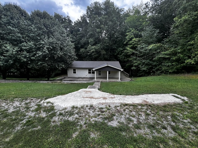 view of front of house featuring a patio, metal roof, and a front yard