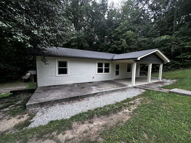 back of property with a patio area, metal roof, and a lawn