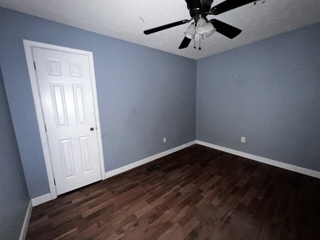 spare room with dark wood-style flooring, ceiling fan, a textured ceiling, and baseboards