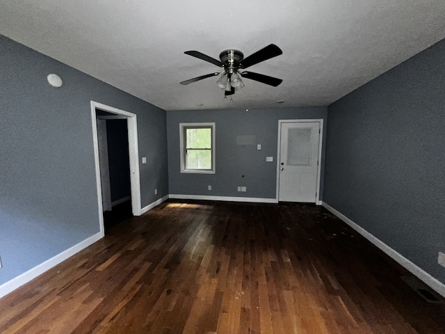 spare room with ceiling fan, dark wood finished floors, and baseboards