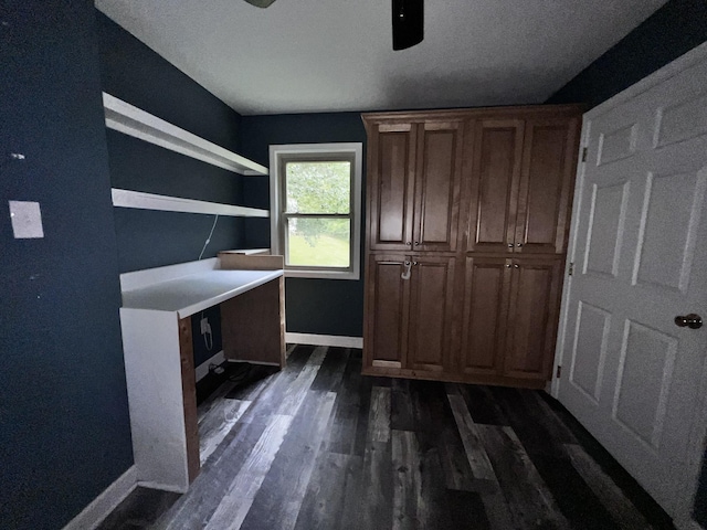 unfurnished office with a ceiling fan, dark wood-style floors, and baseboards