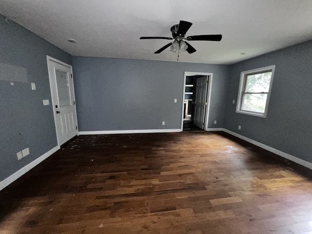 spare room featuring dark wood-type flooring, baseboards, and a ceiling fan