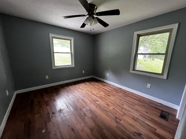 empty room with ceiling fan, baseboards, visible vents, and wood-type flooring