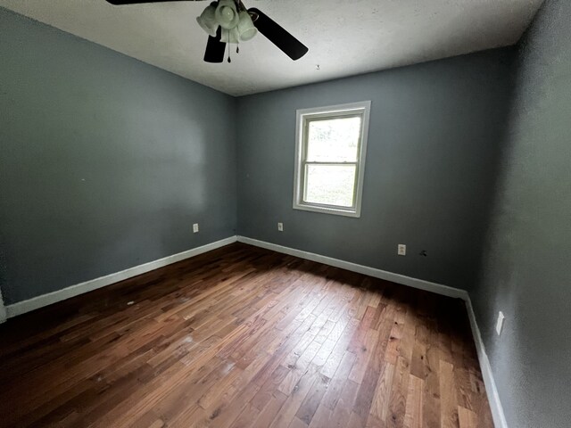 spare room with wood finished floors, a ceiling fan, and baseboards