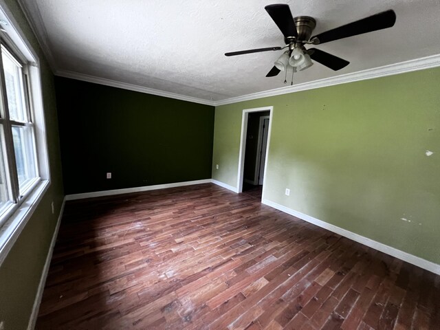 empty room with ornamental molding, dark wood-type flooring, and baseboards