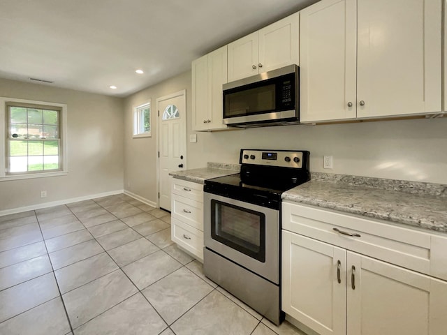 kitchen featuring light stone counters, light tile patterned floors, white cabinets, and appliances with stainless steel finishes