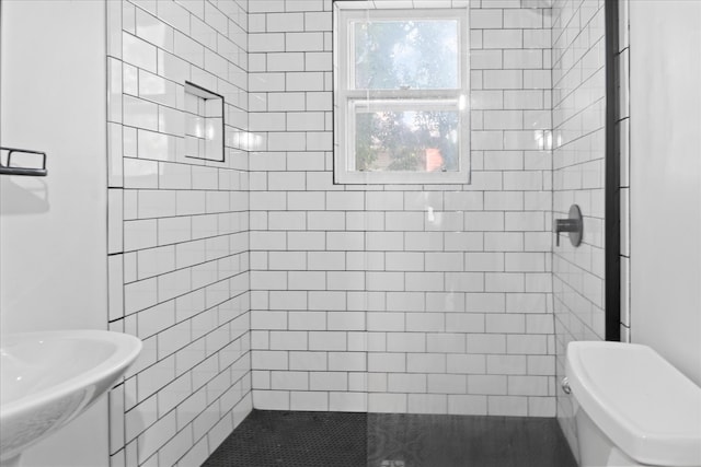 bathroom featuring tiled shower and toilet